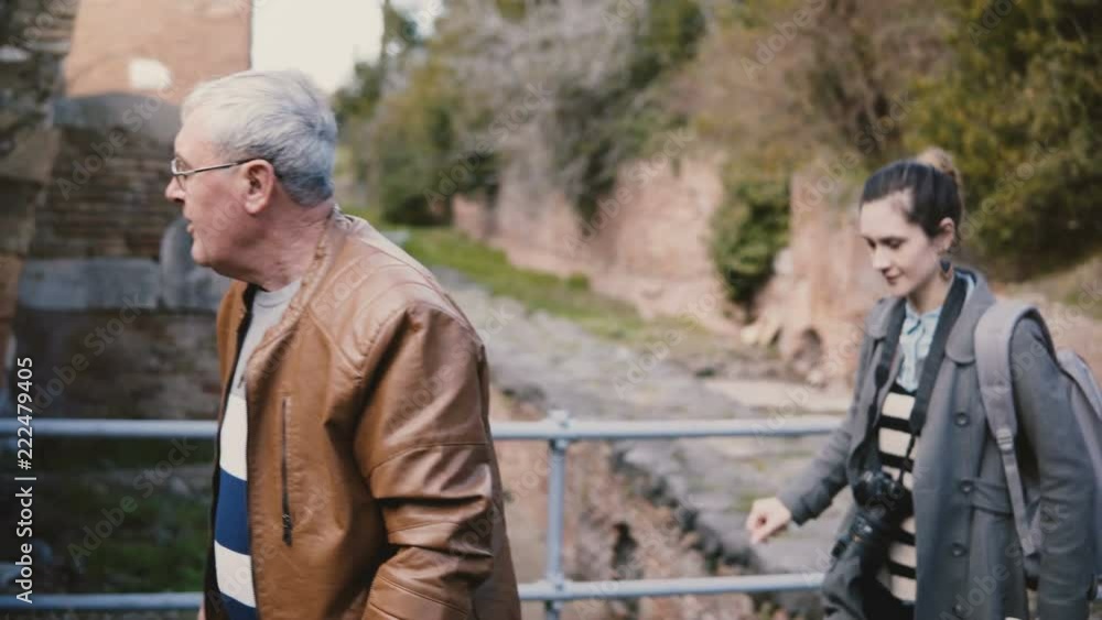 Young European woman and senior man enjoying walking tour around old ruins of Ostia, Italy during family vacation trip. Young European woman and senior man enjoying walking tour around old ruins of Ostia, Italy during family vacation trip.