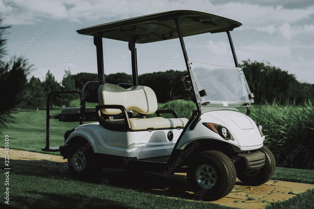 White Little Cart on Golf Field in Sunny Day.