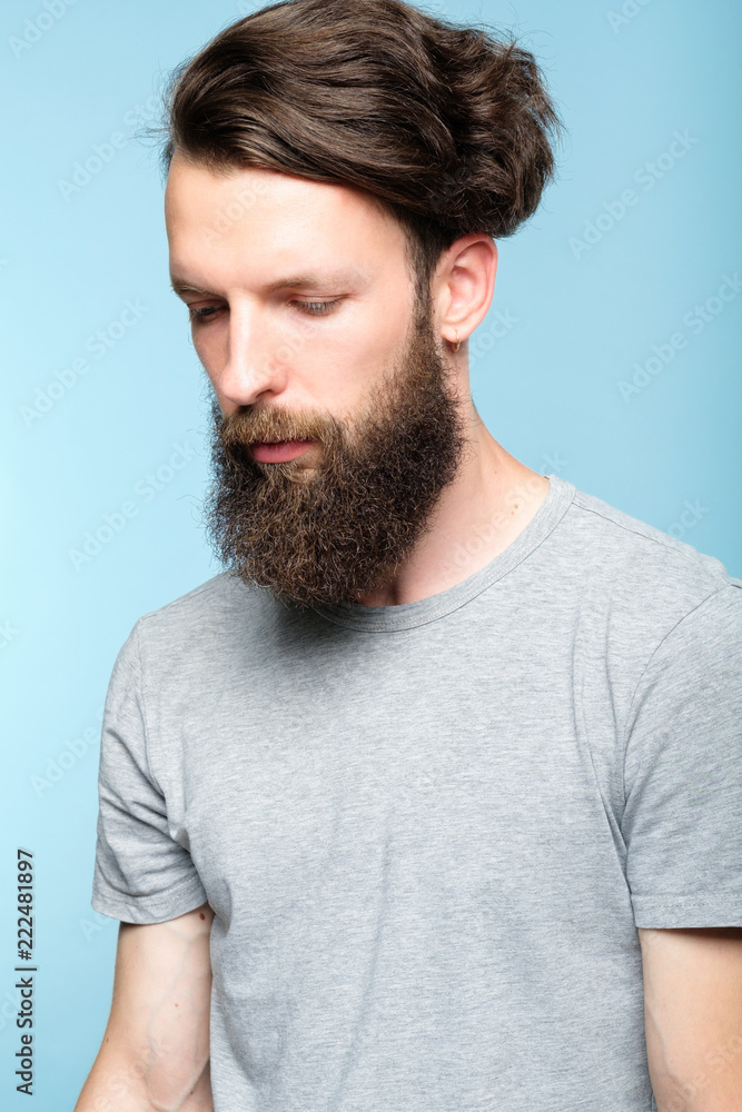Obraz premium sad depressed frustrated dull bearded man. portrait of a disappointed sullen hipster guy on blue background. people emotions and facial expressions concept.