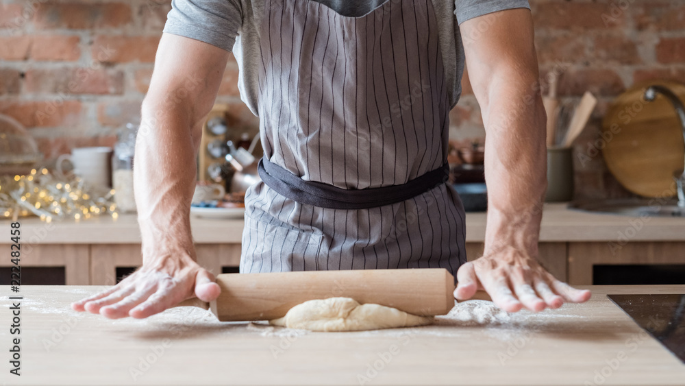 Naklejka premium breadbaking recipe. food preparing and culinary skills concept. unrecognizable man flattening dough using rolling pin.
