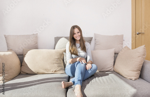1 white girl with long hair in jeans sitting on the couch, young woman smiling, emotions