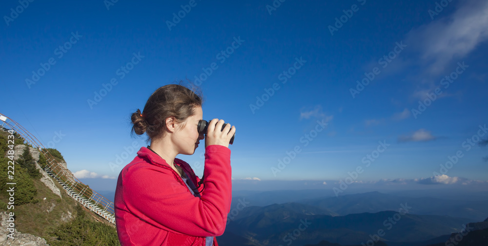 girl looking with binoculars on mountain landscape