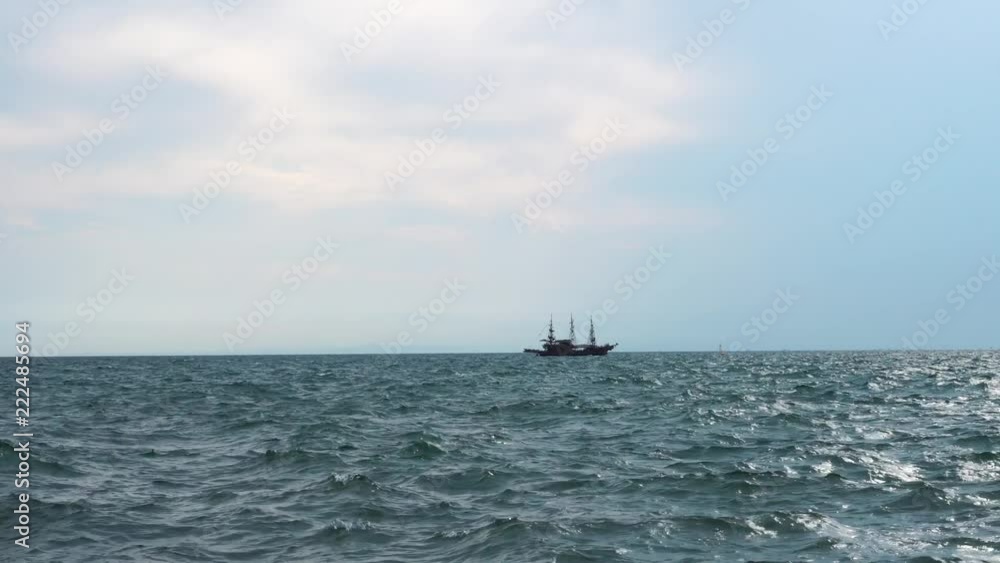 Gorgeous panoramic shot of big old retro sail hip vessel sailing across cloudy seascape horizon in calm ocean waves Gorgeous panoramic shot of big old retro sail hip vessel sailing across cloudy seascape horizon in calm ocean waves
