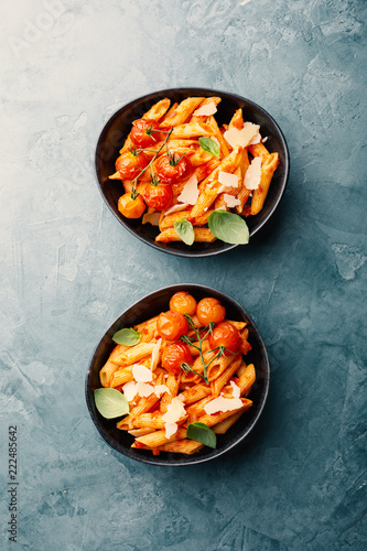 Tasty tomato pasta in bowls on blue table