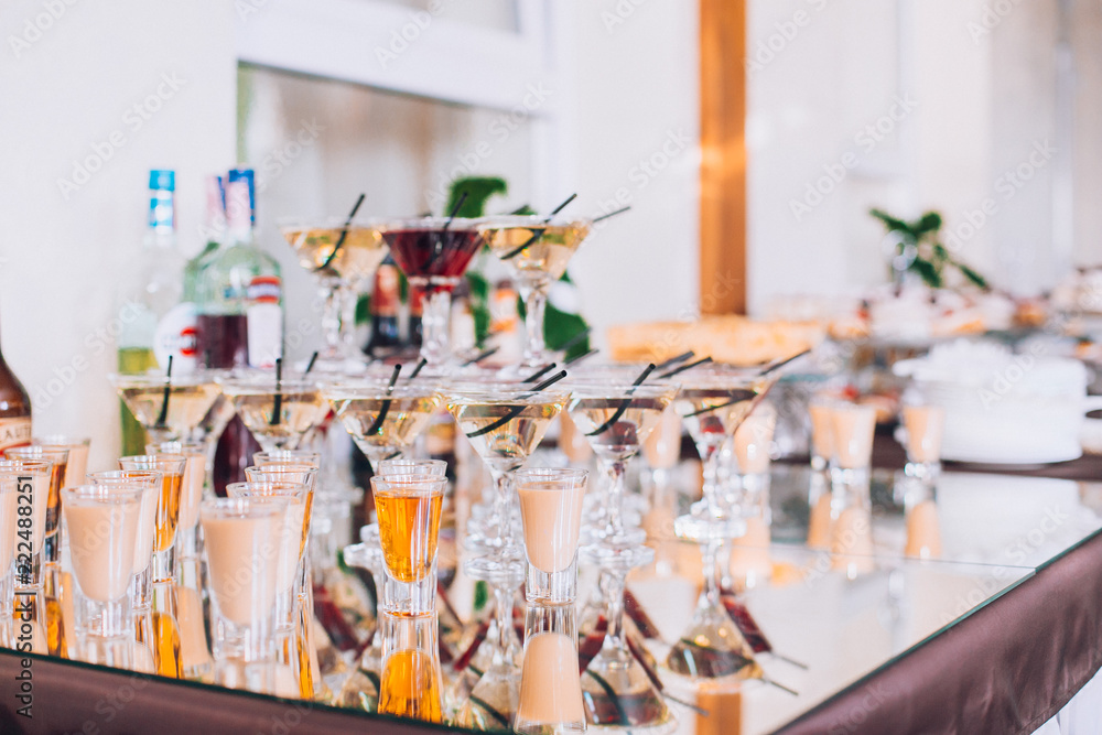 Delicious wedding reception candy bar dessert table. A lot of alcohol and glasses. Coktails and sweets. Wedding party table.