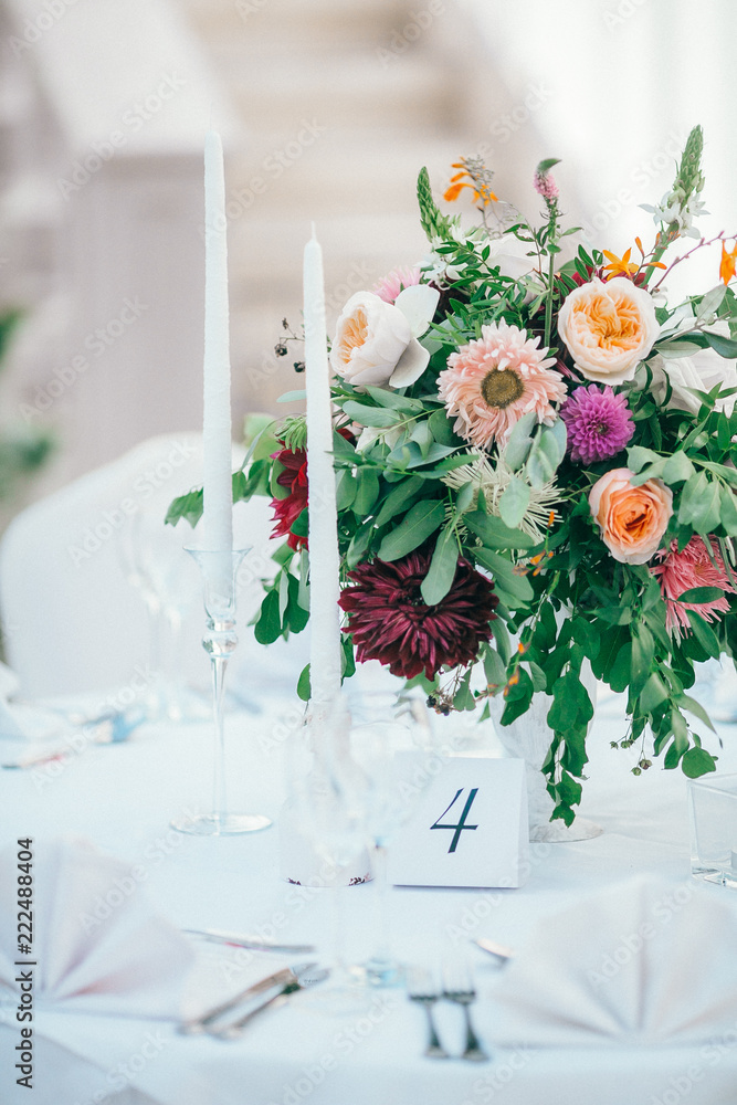 Table set for wedding or another catered event dinner. Catering in restaurant for wedding party. Served tables with pink and red flowers.
