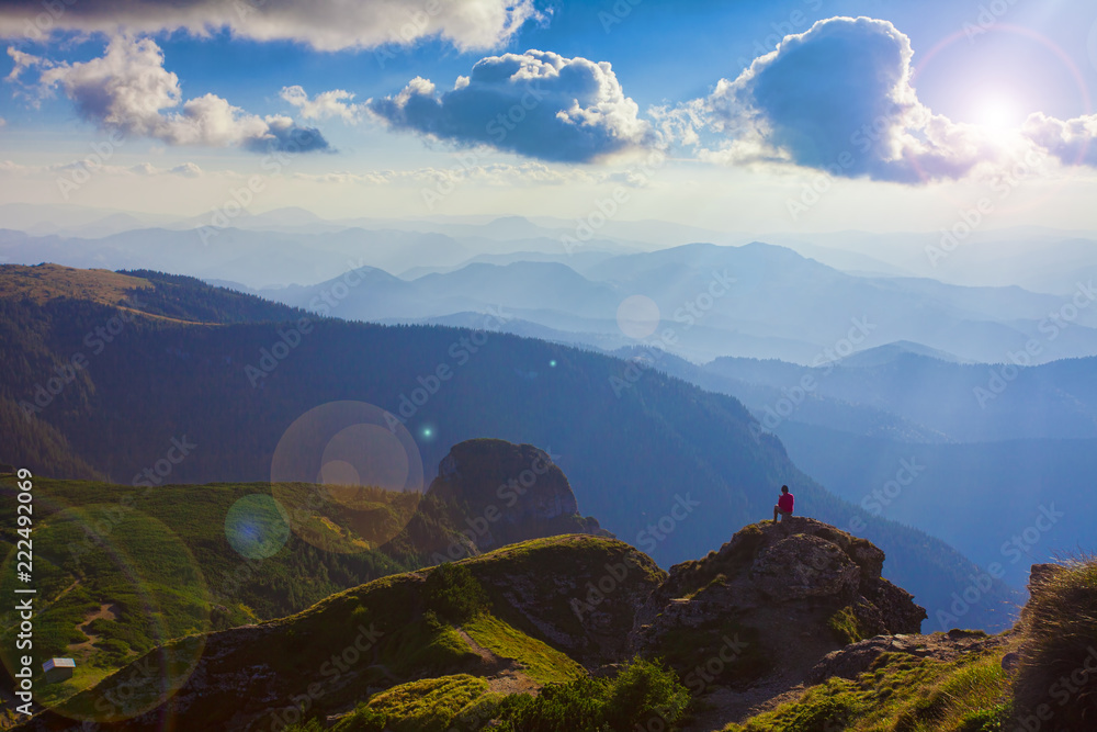person in the beautiful mountain landscape of Ceahlau, Romania. Lens flare added in the photo