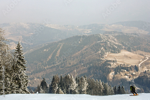 The skier is rolling down from the top of the snow-capped hill on the alpine skiing. Alps, ski resorrt Semmering, Austria. Beautiful view.