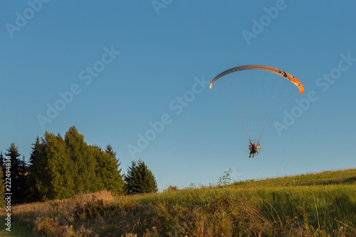 Airplane, parachute with engine. A man with a paragliding fly in the blue sky.