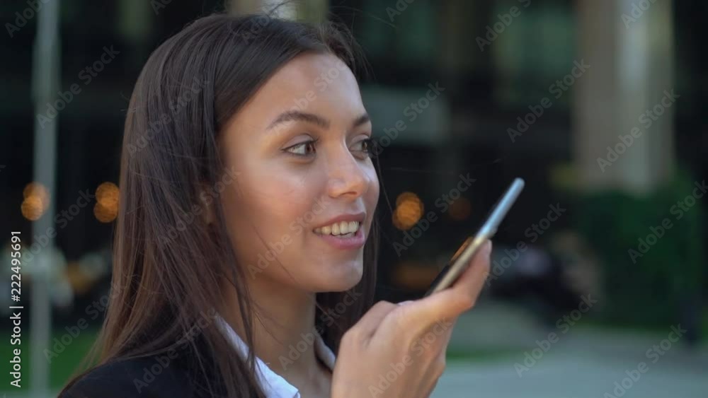 Cheerful young businesswoman talks on phone in summer street Cheerful young businesswoman talks on phone in summer street