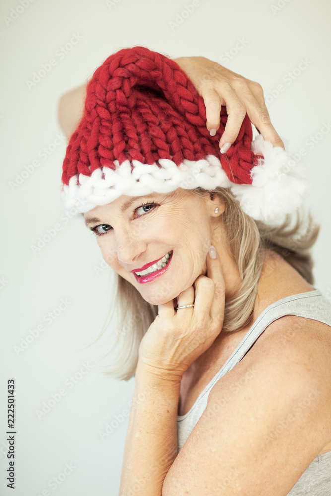 Santas little helper. Beautiful happy senior woman with a santa claus hat, perfect make up, red lipstick, can be used as background Santas little helper. Beautiful happy senior woman with a santa claus hat, perfect make up, red lipstick, can be used as background