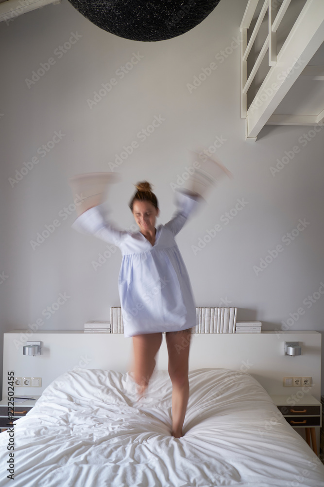 Blurred woman jumping on bed