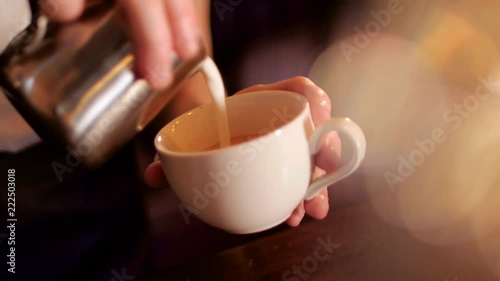 Barista pours milk into coffee in a coffee shop