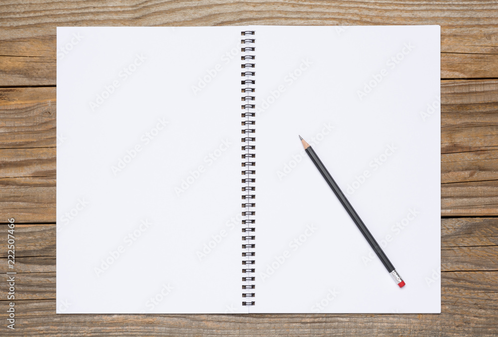 Blank page of a sketchbook with a black pencil, over old wooden texture Blank page of a sketchbook with a black pencil, over old wooden texture