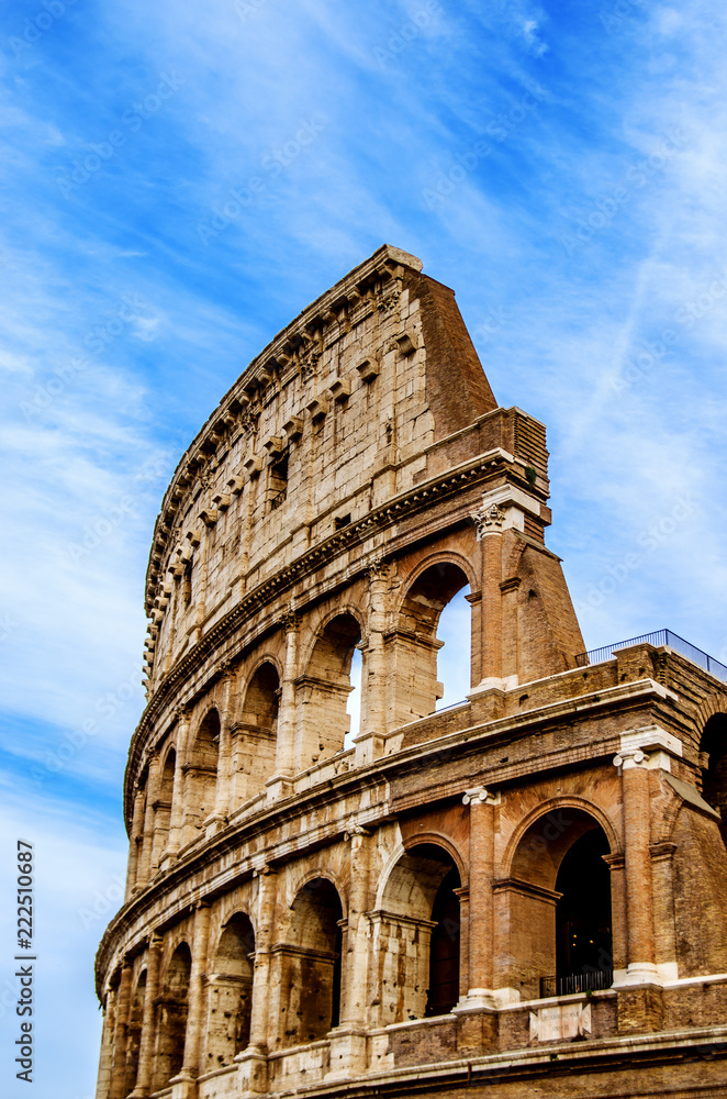 Ancient Colosseum against a blue sky with white traces of floating clouds. Rome. Italy
