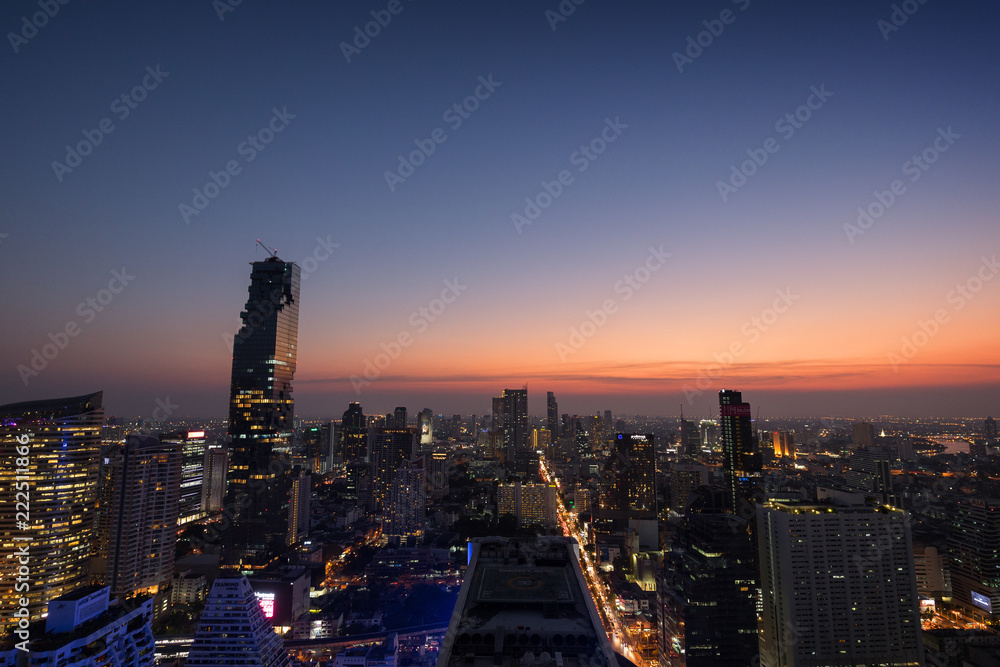 Scenic view of MahaNakhon and many other lit skyscrapers in downtown Bangkok, Thailand, from above in the evening. Copy space.