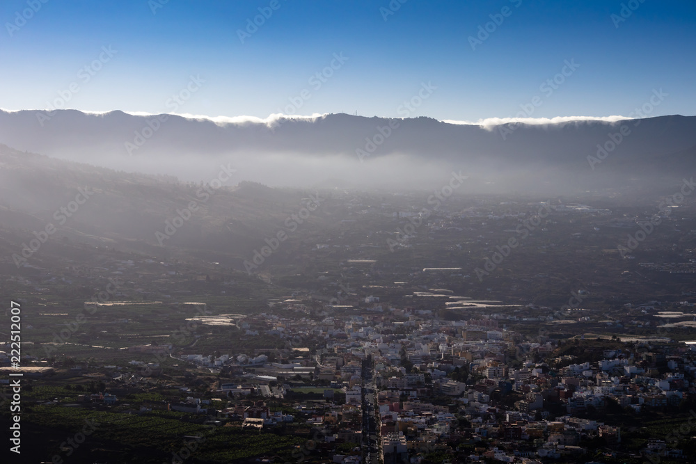 Panoramic view on the valley of the city Los Llanos. Clouds climb over a mountain in the background.