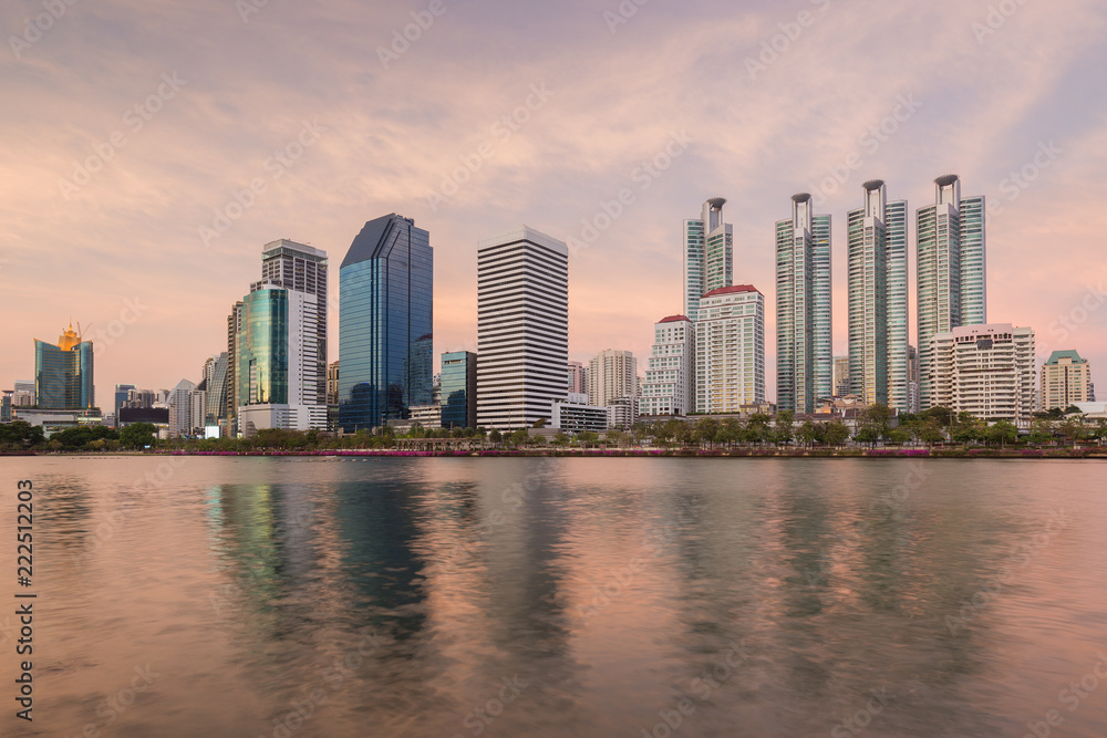 Scenic view of a lake at the Benjakiti (Benjakitti) Park and skyscrapers in Bangkok, Thailand, at sunset.