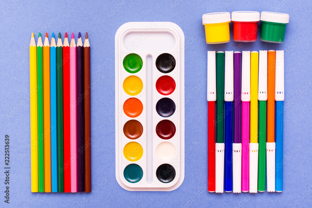 Obraz premium Accessories for drawing - pencils, felt-tip pens, watercolor and gouache blue background. Top View.