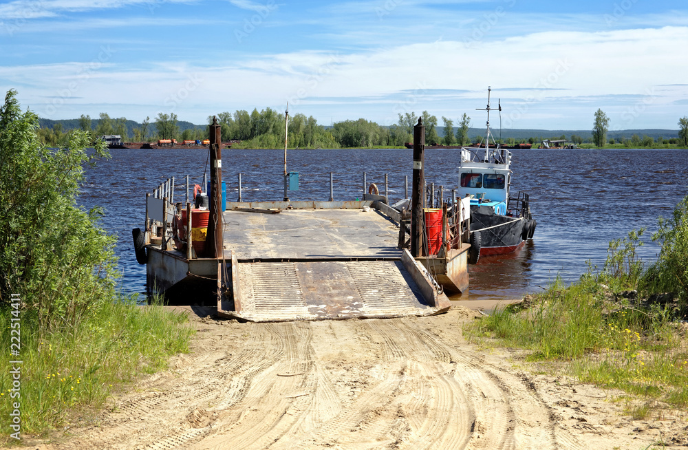 River barge with ramp and boat on the pier near the shore waiting for loading