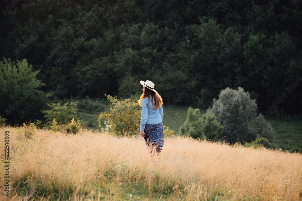 girl in a hat playing with a dog in the field at sunset sun