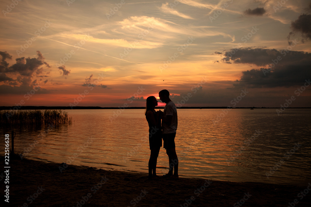 couple in love back light silhouette at lake sunset
