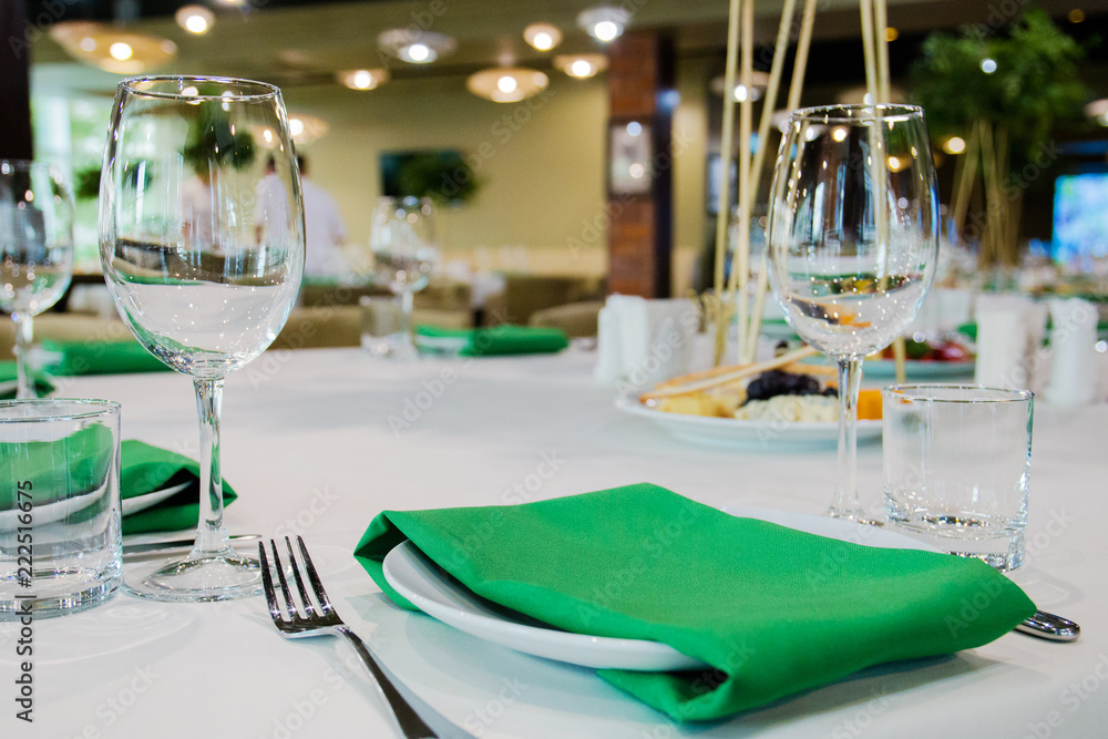 elegant table setting at a banquet for several people, green napkins clean glasses