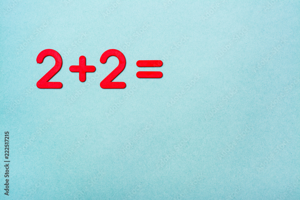 The school task - two plus two - is lined with red plastic figures on a green background. Top View. Copy space The school task - two plus two - is lined with red plastic figures on a green background. Top View. Copy space