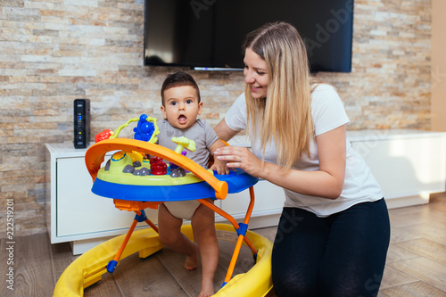 Young and happy mother playing in house with her little son. photo