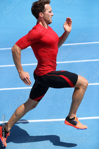 Runner sprinting towards success on run path running athletic track. Goal achievement concept. Male athlete sprinter doing a fast sprint for competition on blue lanes. Track running.