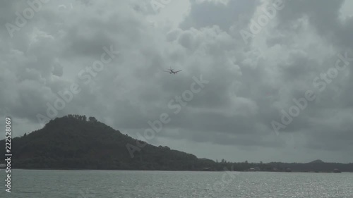 Airplane flying in the cloudy sky over island photo