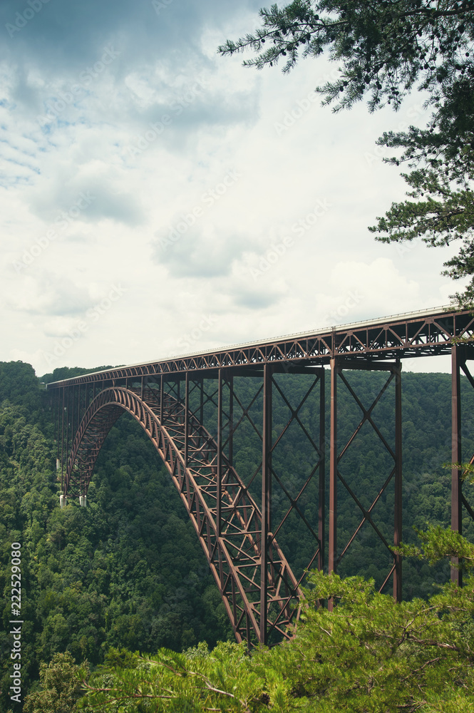 A view of the steel metal arch bridge over the New River Gorge in Fayetteville, West Virginia. The bridge is the longest steel span in the western hemisphere. Repeating lines. Vertical image. A view of the steel metal arch bridge over the New River Gorge in Fayetteville, West Virginia. The bridge is the longest steel span in the western hemisphere. Repeating lines. Vertical image.
