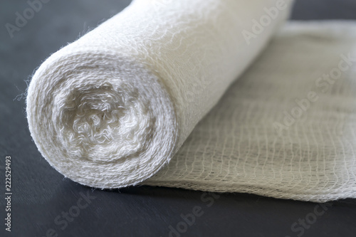 A roll of white medical bandage on a black background.