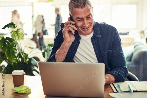 Smiling mature businessman talking on his cellphone at work