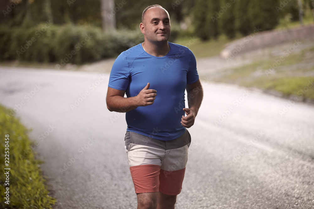 Fototapeta premium one young overweight man, 30-35 years, outdoors nature, jogging, medium shot.
