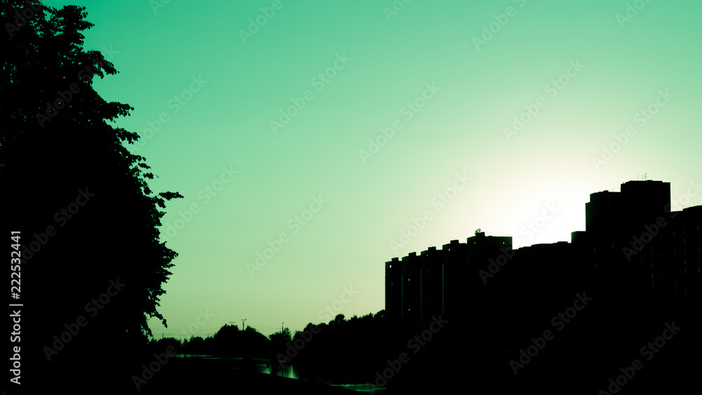 city cyan sky at sunset with strong dark shadows on trees and buildings
