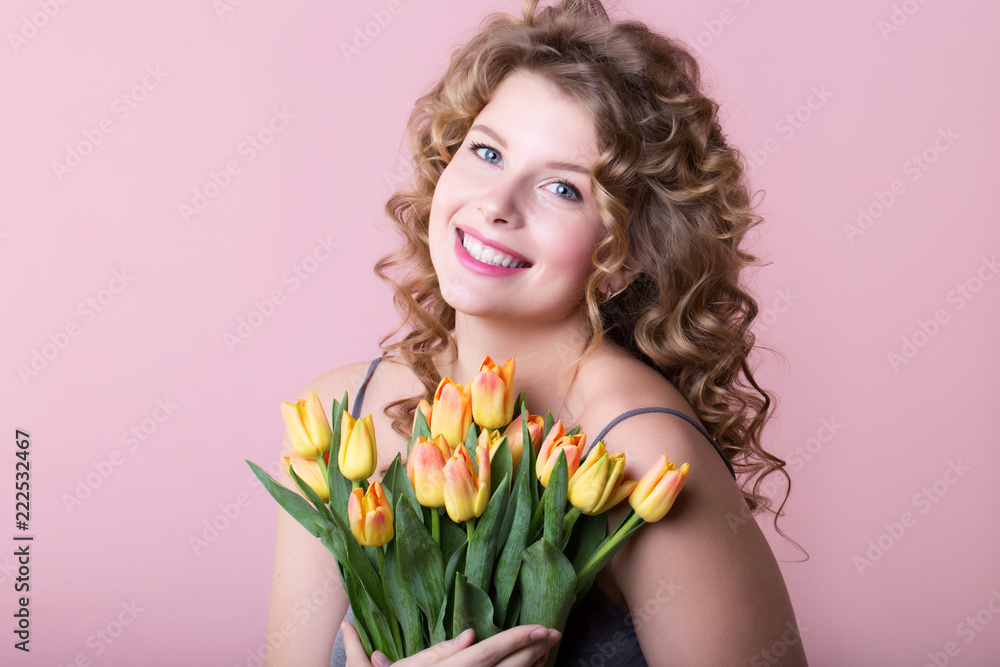 Happy woman with flowers in the pink background.