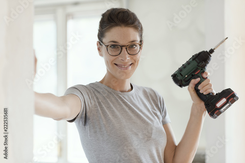 Woman using a drill and working in her new house