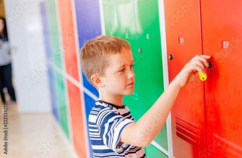 Child boy opening metal school locker.