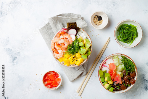 Hawaiian tuna and shrimp poke bowls with seaweed, avocado, mango, pickled ginger, sesame seeds. Top view, overhead, flat lay, copy space