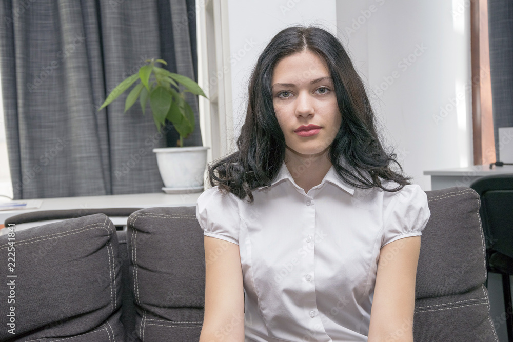 Pretty girl sitting on the grey couch, having rest. Pretty girl sitting on the grey couch, having rest.