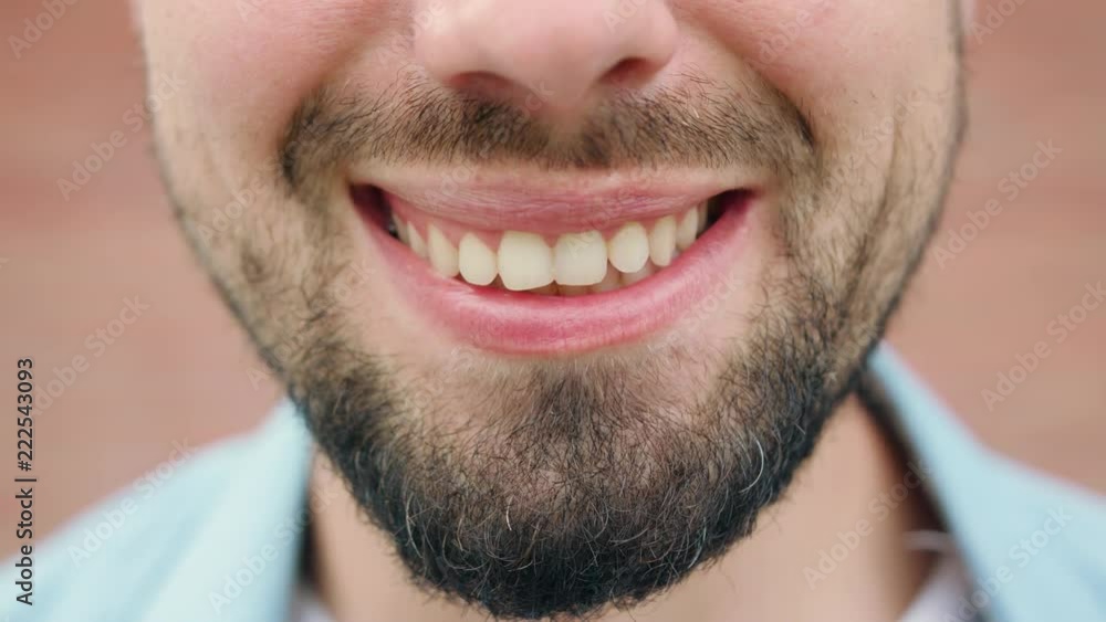 A close-up of a young man's mouth smiling. Macro close-up shot A close-up of a young man's mouth smiling. Macro close-up shot