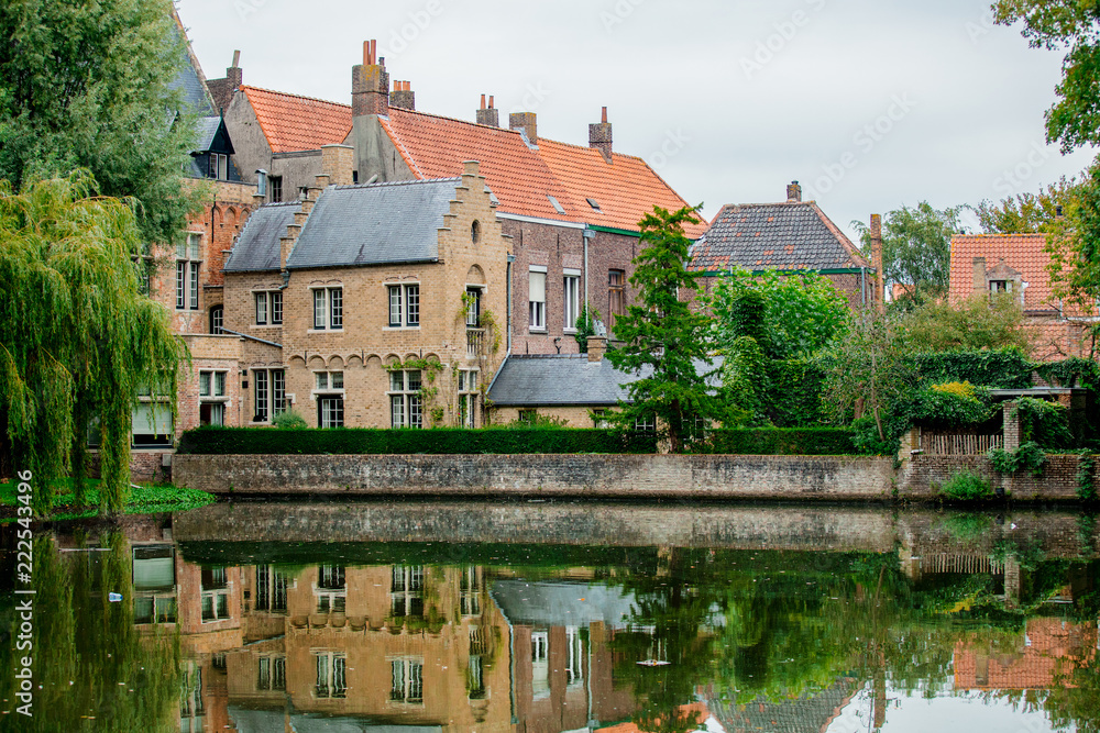 Naklejka premium Old medieval houses near a river, fall season. Bruges, Belgium