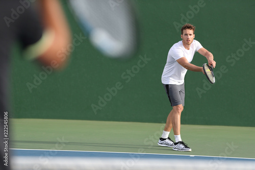 Tennis serve player man serving ball during match point on outdoor green court. Two men athlete playing sport game training doing exercise. © Maridav