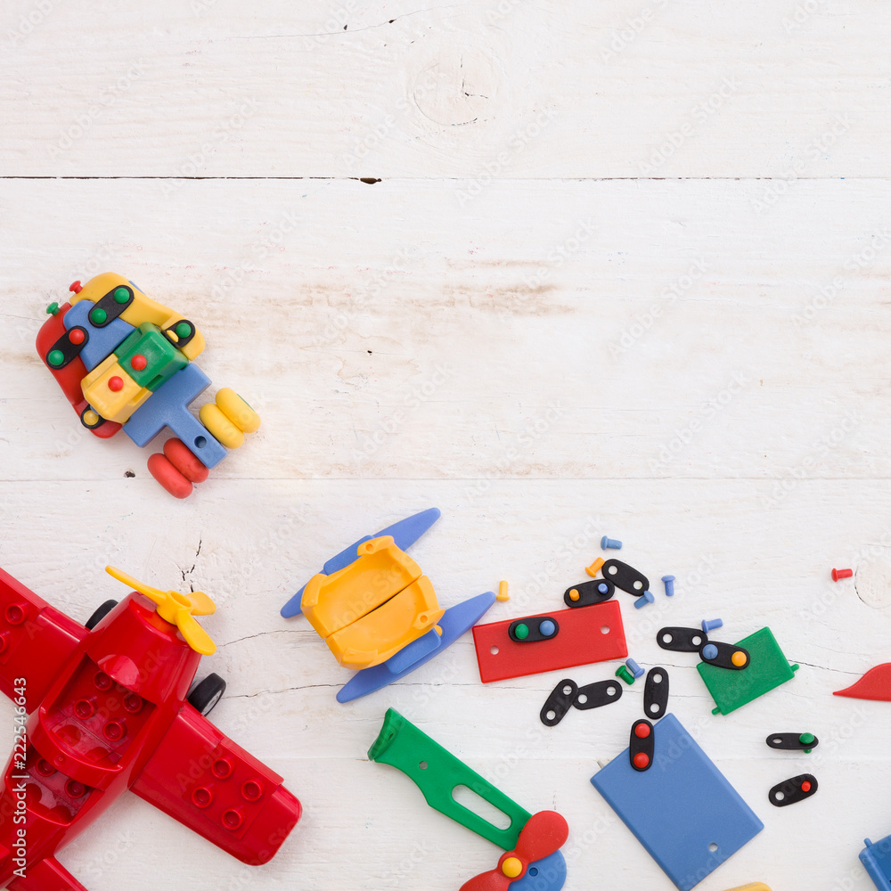 Obraz premium Closeup of multi-color plastic toys and bricks on white wooden background. Early learning and development.