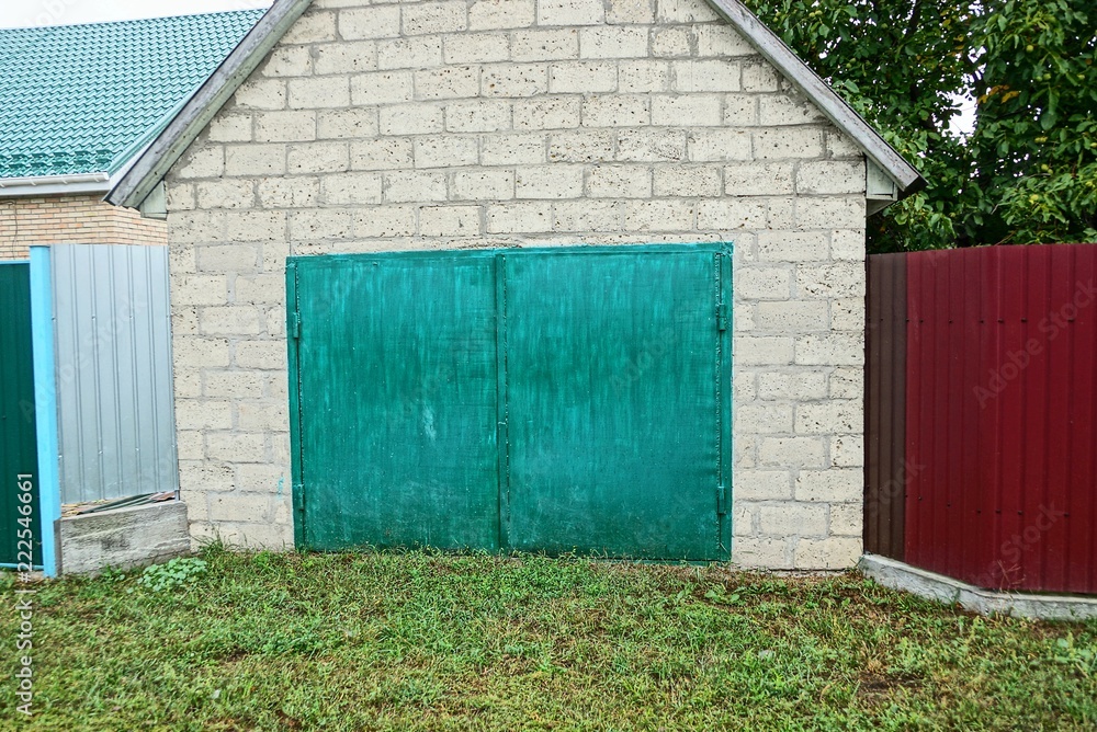 gray brick garage with a glazed green gate in the street gray brick garage with a glazed green gate in the street