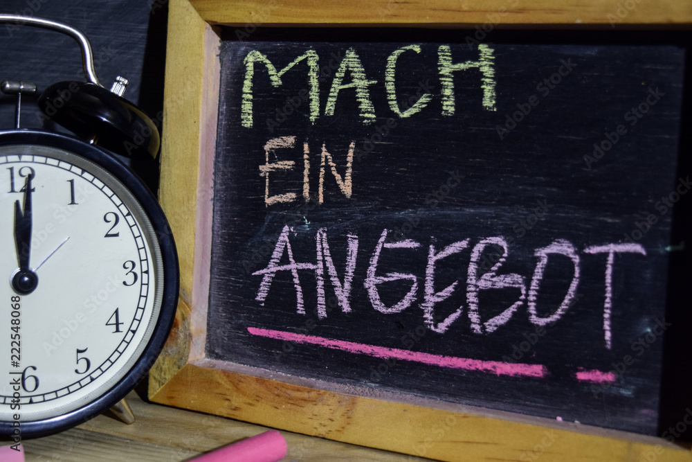 Mach ein angebot in germany on phrase colorful handwritten on blackboard. Education and business concept. Alarm clock, chalk, books on black background Mach ein angebot in germany on phrase colorful handwritten on blackboard. Education and business concept. Alarm clock, chalk, books on black background