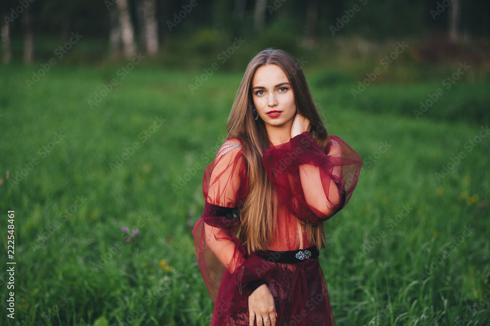 A beautiful young woman in a bard dress is gazing on in the field and the garden. A beautiful young woman in a bard dress is gazing on in the field and the garden.