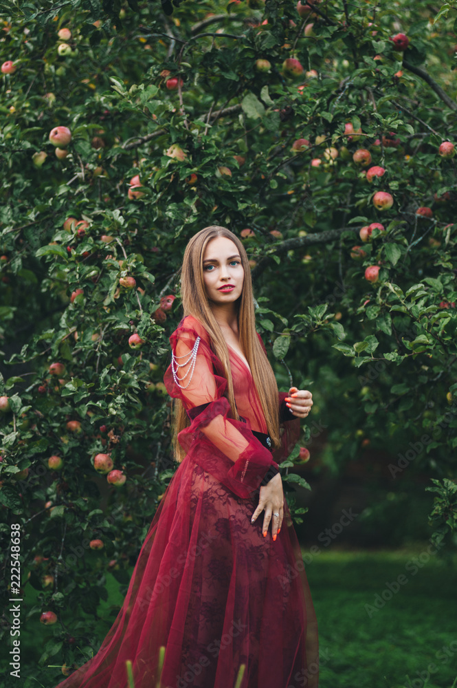 A beautiful young woman in a bard dress is gazing on in the field and the garden.