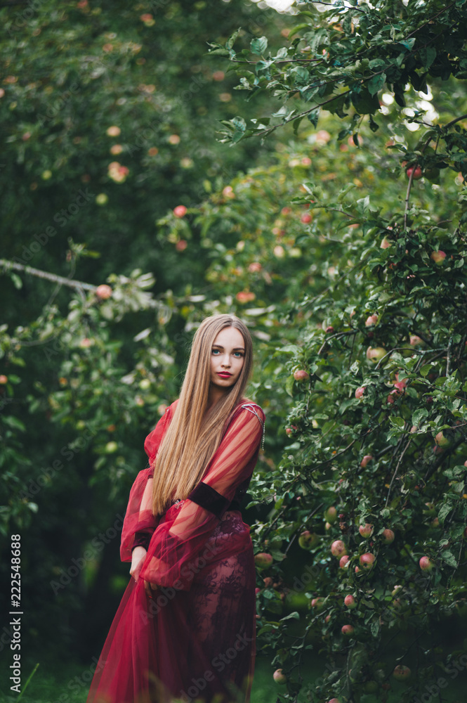 A beautiful young woman in a bard dress is gazing on in the field and the garden. A beautiful young woman in a bard dress is gazing on in the field and the garden.